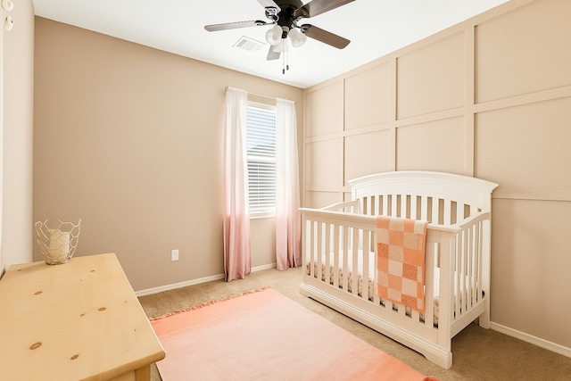 bedroom with a crib, baseboards, visible vents, and light colored carpet
