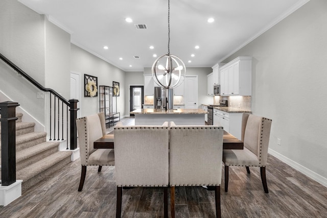dining room featuring a chandelier, ornamental molding, baseboards, visible vents, and dark wood-type flooring
