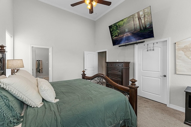 bedroom with a high ceiling, a ceiling fan, baseboards, ornamental molding, and light colored carpet
