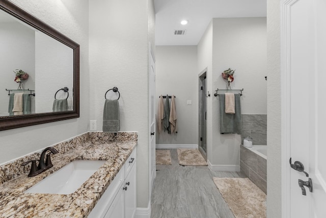 bathroom with marble finish floor, vanity, visible vents, a stall shower, and a garden tub