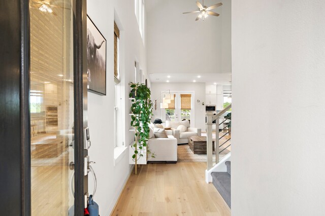 foyer featuring a towering ceiling, stairway, french doors, a ceiling fan, and light wood-style flooring