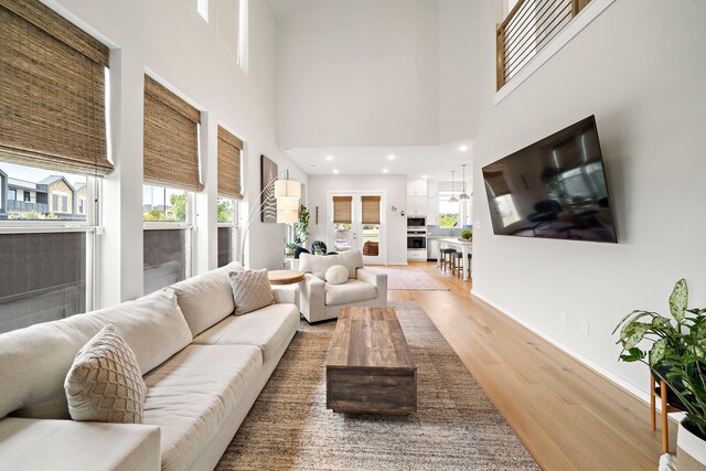 living room with plenty of natural light, wood finished floors, and a high ceiling