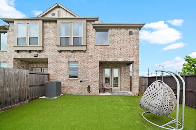rear view of property featuring brick siding, a fenced backyard, a yard, and central AC unit