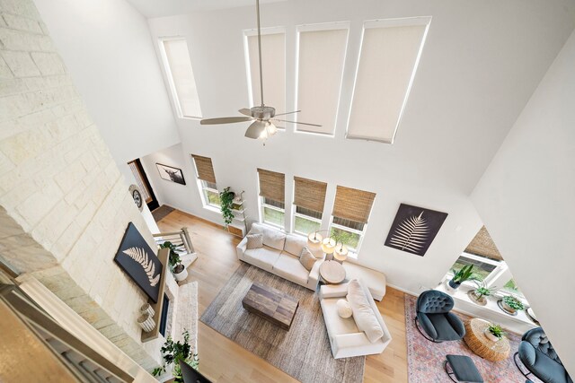 living area with a ceiling fan, wood finished floors, and a towering ceiling
