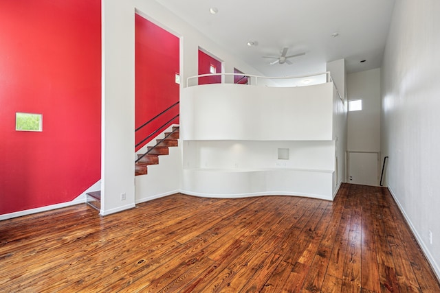 unfurnished room with a ceiling fan, hardwood / wood-style flooring, and stairs