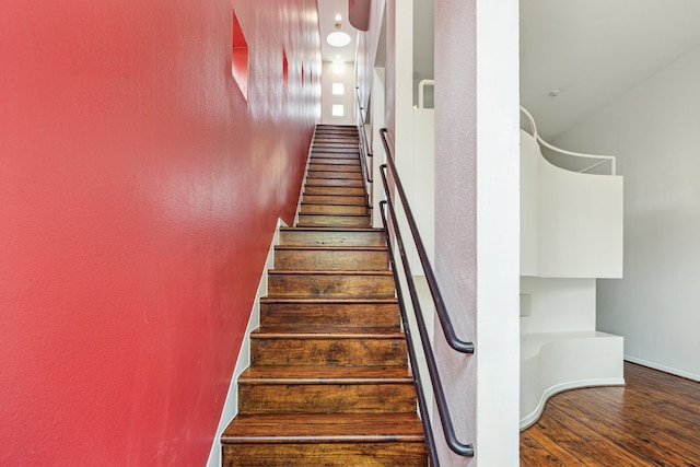 stairs with baseboards, a textured wall, and wood finished floors