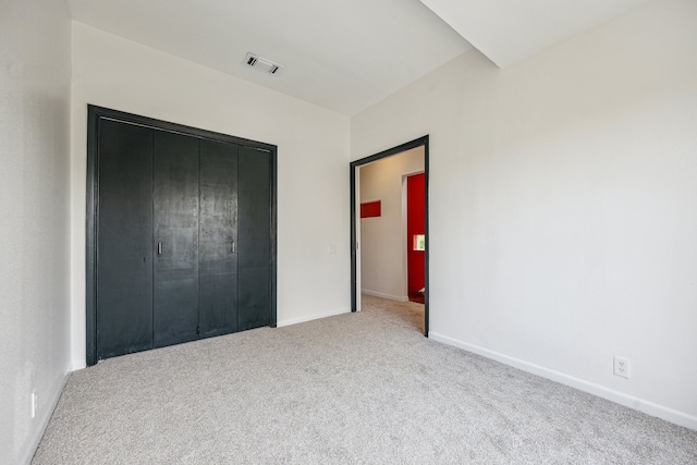 unfurnished bedroom featuring visible vents, baseboards, a closet, and light carpet