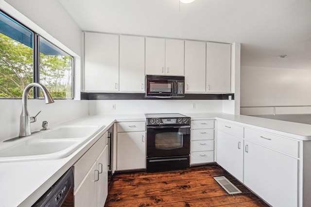 kitchen with light countertops, dark wood finished floors, a sink, and black appliances