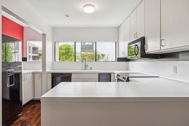 kitchen featuring a sink, dark wood-style flooring, black appliances, and light countertops