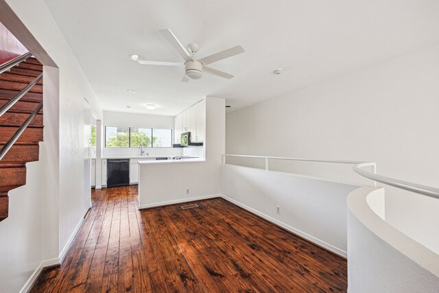 unfurnished room with ceiling fan, a sink, dark wood finished floors, stairs, and baseboards