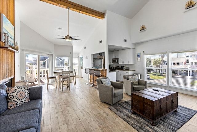living area featuring beam ceiling, high vaulted ceiling, a ceiling fan, visible vents, and light wood-style flooring