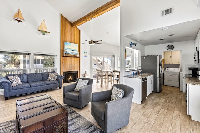 living room featuring visible vents, washing machine and clothes dryer, high vaulted ceiling, and a ceiling fan