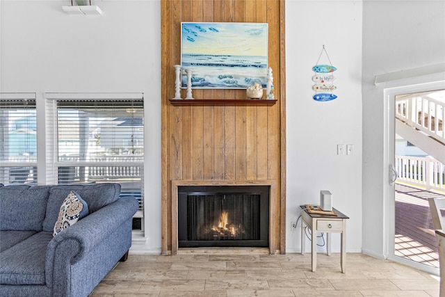 living room featuring stairway, wood finished floors, and a warm lit fireplace