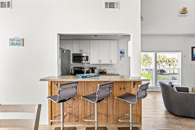 kitchen featuring tasteful backsplash, visible vents, stainless steel appliances, and light wood finished floors