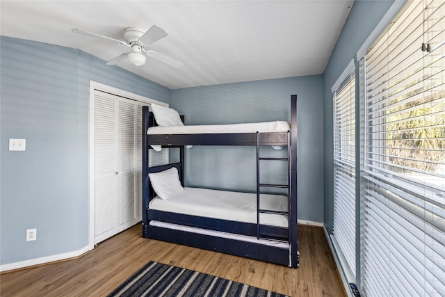 unfurnished bedroom featuring baseboards, wood finished floors, a ceiling fan, and a closet