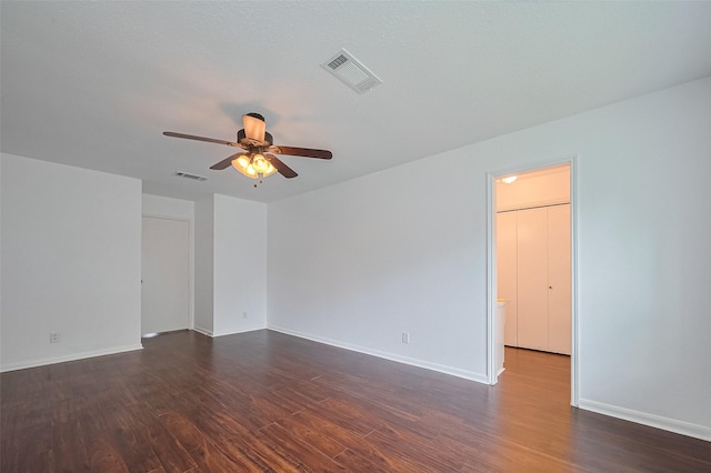 spare room featuring dark wood-type flooring, visible vents, and ceiling fan