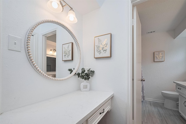 bathroom with toilet, visible vents, vanity, and baseboards