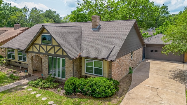 view of front of property featuring concrete driveway, roof with shingles, stone siding, and a chimney