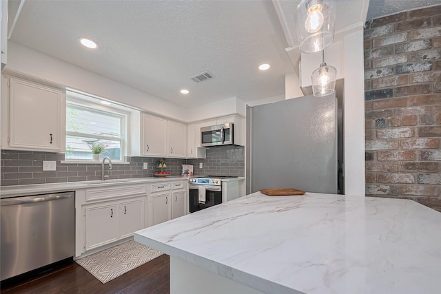 kitchen with a sink, stainless steel appliances, tasteful backsplash, visible vents, and white cabinets