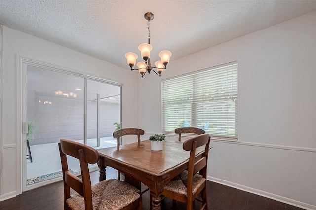 dining room with a textured ceiling, dark wood-style flooring, a chandelier, and baseboards
