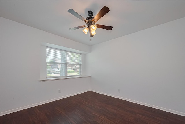 empty room with dark wood-style flooring, a ceiling fan, and baseboards