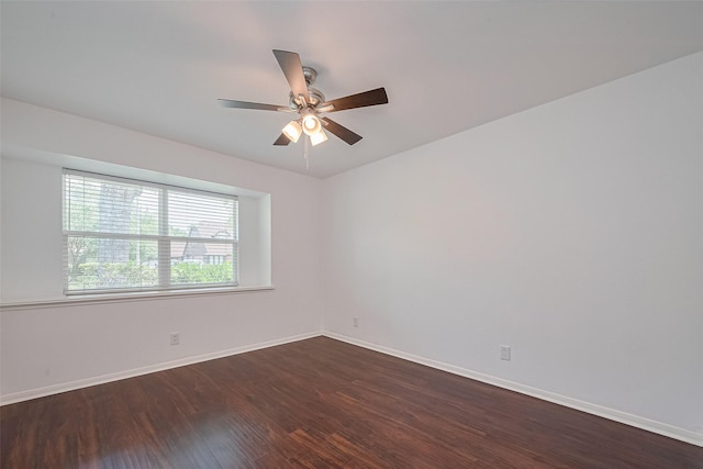 empty room featuring ceiling fan, baseboards, and dark wood finished floors