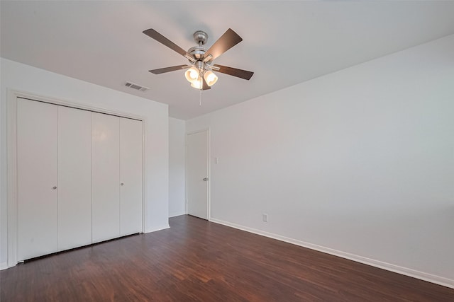 unfurnished bedroom featuring dark wood-style floors, visible vents, a closet, and baseboards