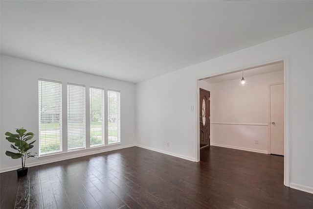 unfurnished room with baseboards and dark wood-style floors