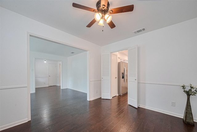 unfurnished room featuring baseboards, visible vents, ceiling fan, and dark wood-type flooring