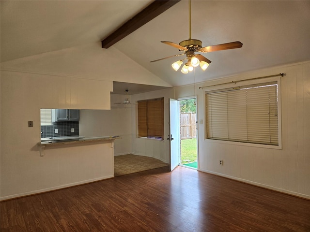 unfurnished living room with wood finished floors, ceiling fan, lofted ceiling with beams, and baseboards