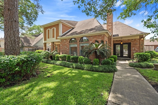 8310 Mentmore Dr, Spring, TX 77379 - view of front of house with french doors, brick siding, a front lawn, and a chimney