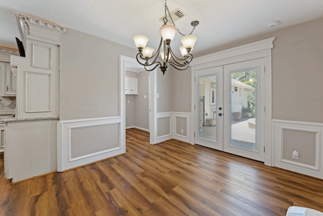 8310 Mentmore Dr, Spring, TX 77379 - unfurnished dining area with a chandelier, french doors, wood finished floors, wainscoting, and a decorative wall