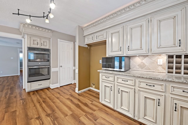 8310 Mentmore Dr, Spring, TX 77379 - kitchen featuring appliances with stainless steel finishes, tasteful backsplash, light wood finished floors, and baseboards