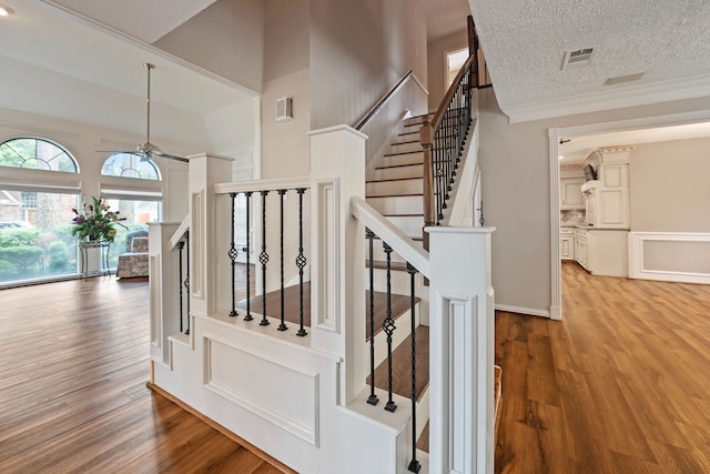 8310 Mentmore Dr, Spring, TX 77379 - staircase featuring wood finished floors, a ceiling fan, crown molding, and a textured ceiling