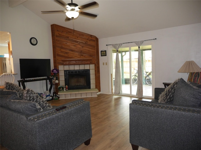 living room featuring a ceiling fan, light wood finished floors, lofted ceiling, and a fireplace