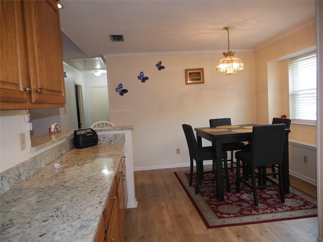 dining space with visible vents, ornamental molding, hardwood / wood-style floors, baseboards, and attic access