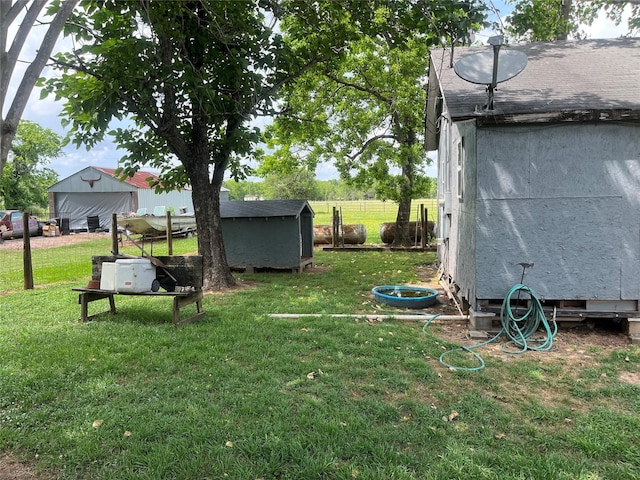 view of yard featuring a storage unit, fence, and an outdoor structure
