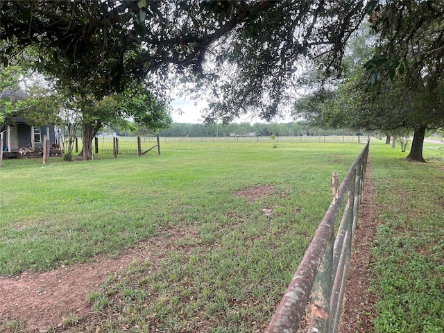view of yard with fence and a rural view