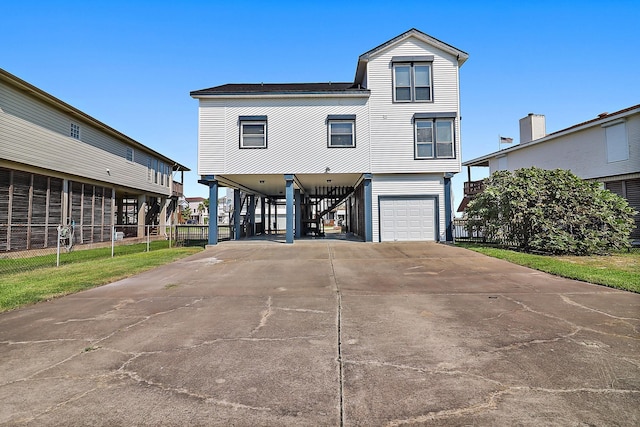coastal home with driveway, fence, a carport, and a garage