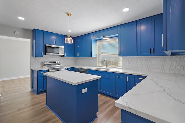 kitchen with a sink, stainless steel appliances, tasteful backsplash, light stone counters, and blue cabinets