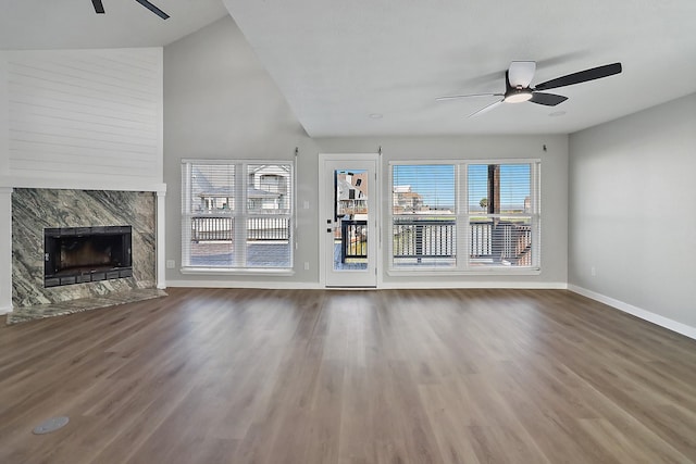 unfurnished living room with wood finished floors, a ceiling fan, a premium fireplace, and baseboards