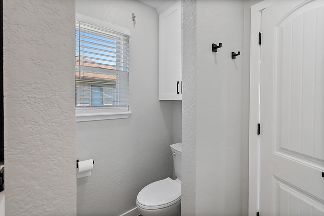 bathroom with toilet and a textured wall