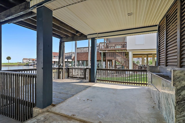 view of patio with stairway and a deck with water view