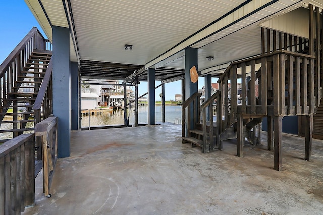 view of patio with a boat dock, a water view, stairway, and boat lift