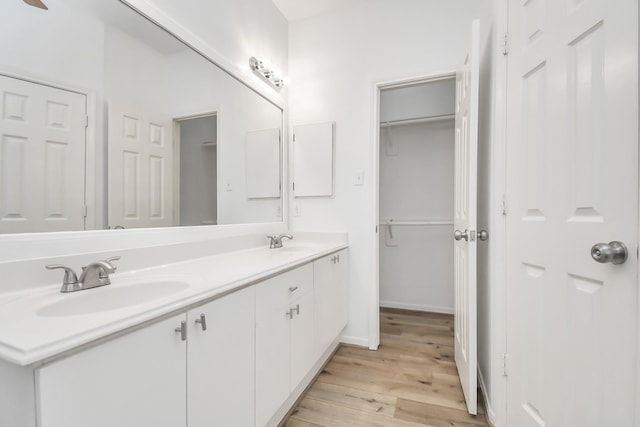 full bathroom with double vanity, a sink, wood finished floors, and baseboards