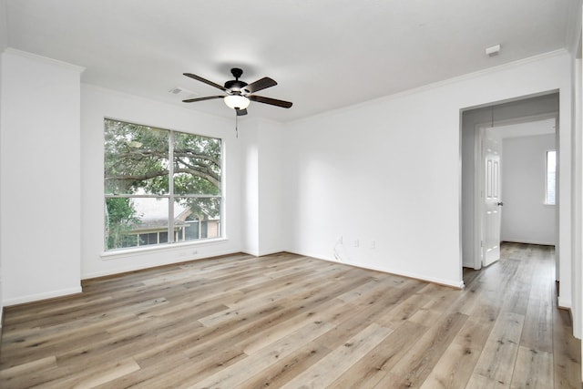 spare room featuring crown molding, light wood-style floors, and a healthy amount of sunlight