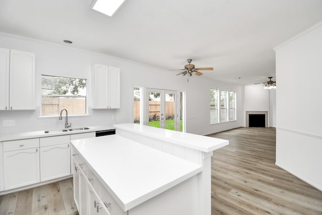 kitchen with light wood-style floors, a sink, a kitchen island, and white cabinetry