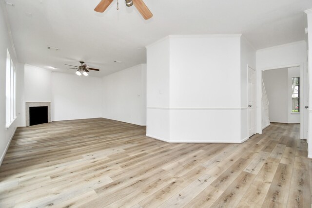 unfurnished living room featuring baseboards, ceiling fan, a fireplace, and light wood-style flooring