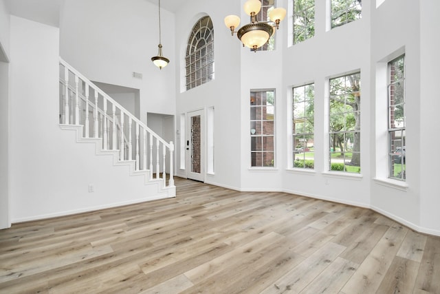 foyer entrance with a high ceiling, a wealth of natural light, and wood finished floors