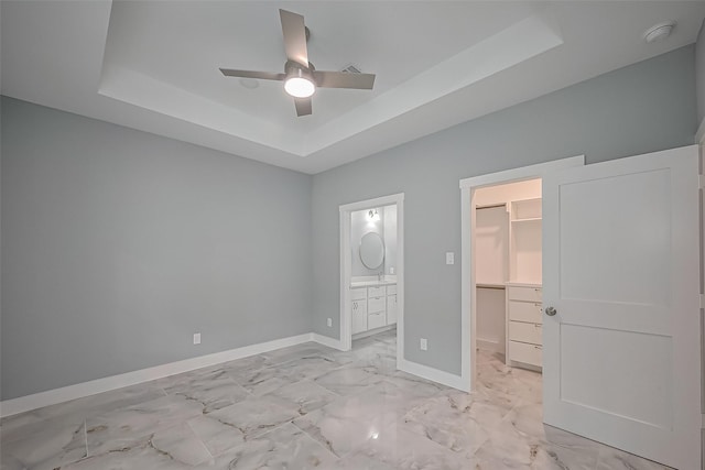403 Smith St, Dayton, TX 77535 - unfurnished bedroom featuring a walk in closet, baseboards, a raised ceiling, a closet, and marble finish floor